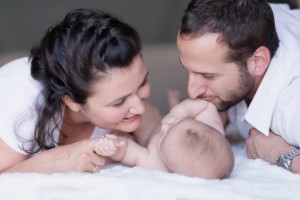 Mother and father kissing baby