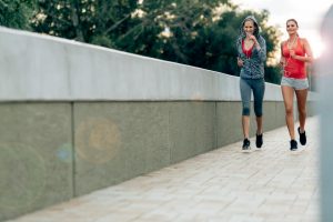 Active female joggers running outdoors and listening to music